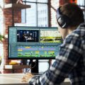 Remotely working videographer in home office doing video montage using specialized software applications. Video editor using editing tools on PC to cut movie project footage in home office